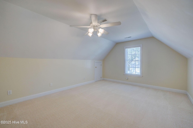 additional living space with visible vents, a ceiling fan, light carpet, vaulted ceiling, and baseboards