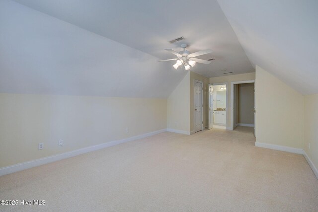 additional living space with light colored carpet, visible vents, vaulted ceiling, ceiling fan, and baseboards