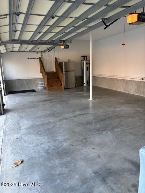 garage featuring water heater, freestanding refrigerator, and a garage door opener