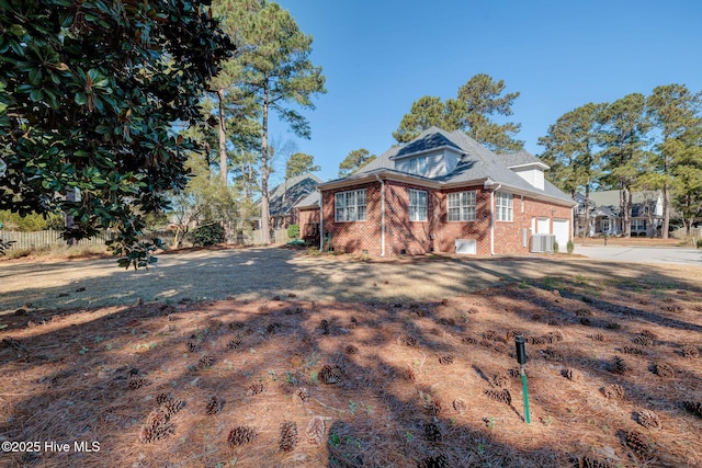 view of front of house featuring brick siding, fence, a garage, cooling unit, and driveway