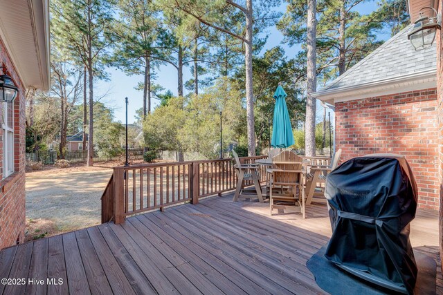 wooden deck featuring grilling area, fence, and outdoor dining area