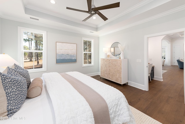 bedroom with ornamental molding, dark hardwood / wood-style flooring, and a raised ceiling