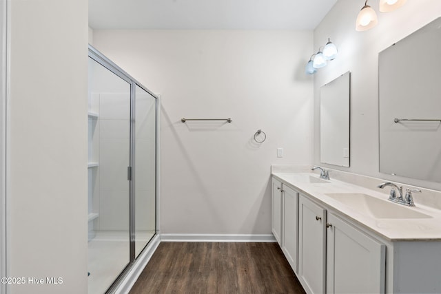 full bath with a shower stall, baseboards, a sink, and wood finished floors