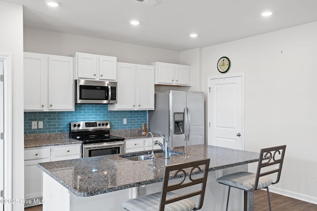 kitchen featuring stainless steel appliances, a sink, backsplash, and a breakfast bar area