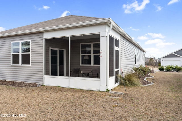 back of property featuring a sunroom, a shingled roof, and a lawn