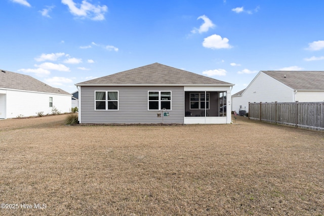 back of house with a shingled roof, fence, and a lawn