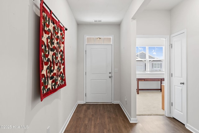 doorway with dark wood-type flooring, visible vents, and baseboards