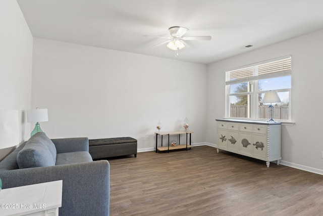 living area with visible vents, ceiling fan, baseboards, and wood finished floors