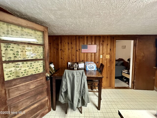 interior space with a textured ceiling and wood walls