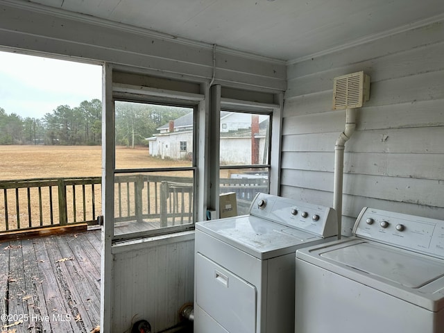 washroom with wood-type flooring, washer and dryer, and wood walls