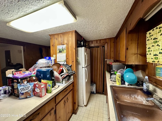 kitchen featuring white refrigerator, sink, and a textured ceiling