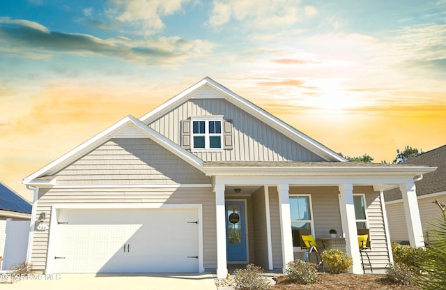 view of front of home with an attached garage, covered porch, driveway, and board and batten siding