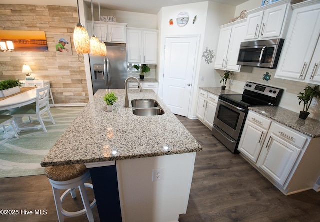 kitchen with white cabinets, a kitchen island with sink, stainless steel appliances, and a sink