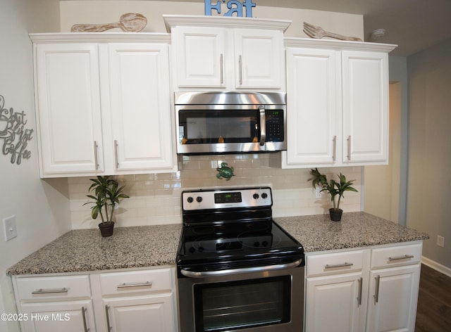 kitchen featuring appliances with stainless steel finishes, white cabinets, decorative backsplash, and light stone counters