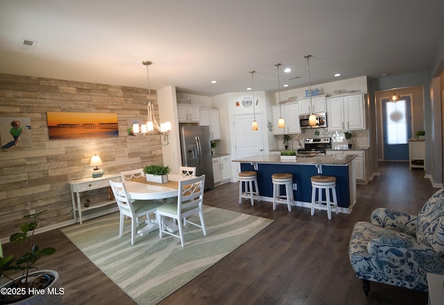 dining area featuring a notable chandelier, recessed lighting, wooden walls, dark wood-style flooring, and visible vents