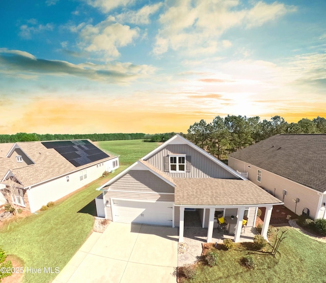 view of front of property with board and batten siding, a front yard, driveway, and an attached garage