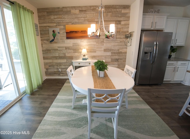 dining room featuring plenty of natural light, dark wood finished floors, a notable chandelier, and wood walls