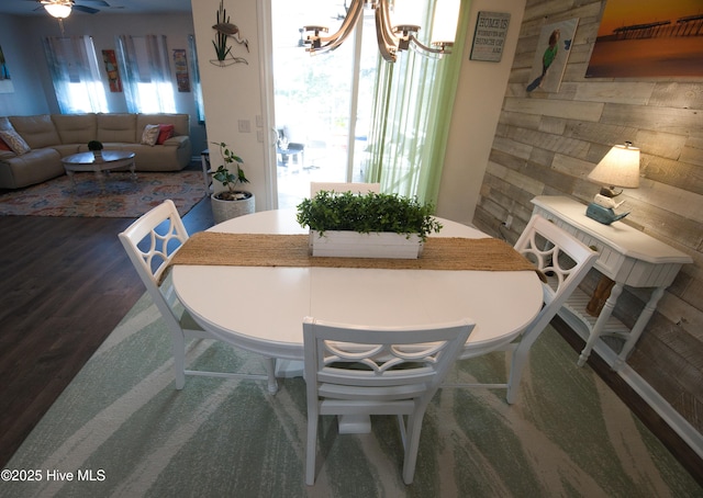 dining space featuring dark wood finished floors and ceiling fan with notable chandelier