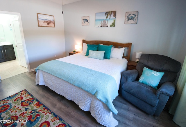 bedroom with ensuite bathroom, wood finished floors, and baseboards