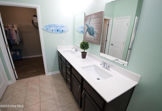 full bathroom with double vanity, tile patterned flooring, a sink, and a walk in closet