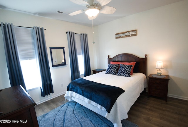 bedroom featuring dark wood-style floors, visible vents, baseboards, and a ceiling fan