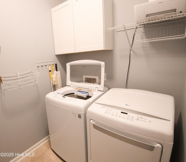 clothes washing area with baseboards, cabinet space, washing machine and clothes dryer, and light tile patterned floors