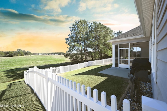 view of yard with ceiling fan, a patio area, a fenced backyard, and a sunroom