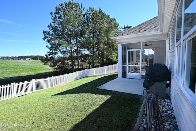 view of yard featuring a sunroom, a fenced backyard, a ceiling fan, and a patio