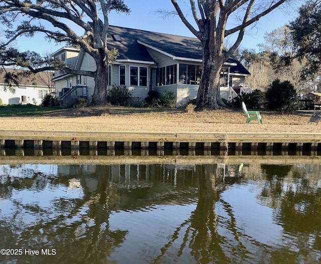 rear view of house with a sunroom and a water view