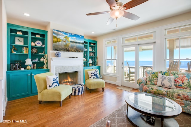 living area featuring a fireplace, light hardwood / wood-style floors, and ceiling fan