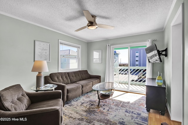 living room featuring ornamental molding, wood-type flooring, a textured ceiling, and ceiling fan