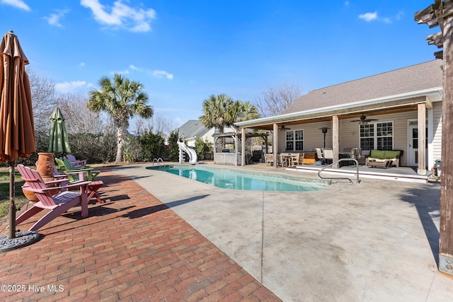 pool featuring ceiling fan, a water slide, exterior bar, an outdoor living space, and a patio area