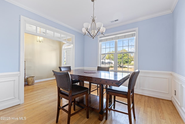 dining space with light wood-style flooring, visible vents, a notable chandelier, and ornamental molding