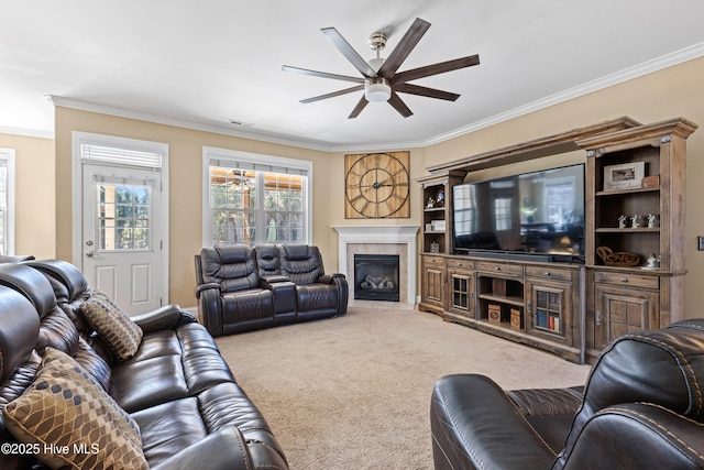 living room featuring carpet, a fireplace, ornamental molding, and ceiling fan