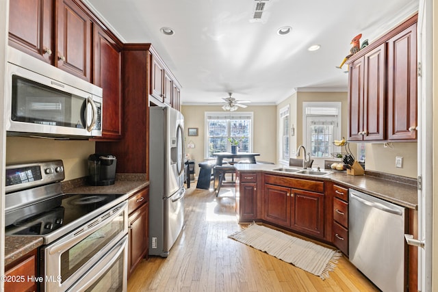 kitchen featuring stainless steel appliances, dark countertops, a sink, and dark brown cabinets