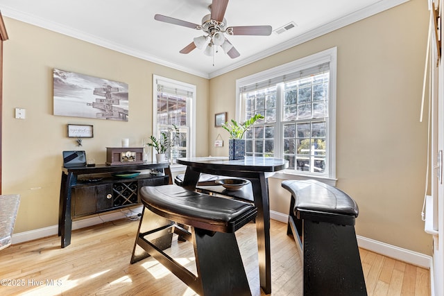 dining room with a ceiling fan, baseboards, visible vents, light wood finished floors, and crown molding