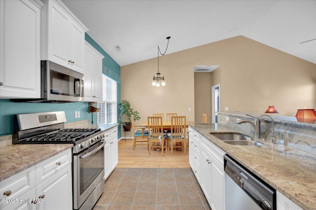 kitchen with appliances with stainless steel finishes, pendant lighting, white cabinetry, sink, and light stone counters