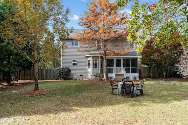 rear view of house with a sunroom, a yard, and a fire pit