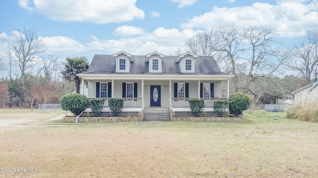 new england style home featuring a front yard, covered porch, and fence