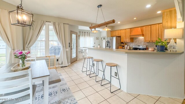 kitchen with decorative backsplash, appliances with stainless steel finishes, a peninsula, premium range hood, and a sink