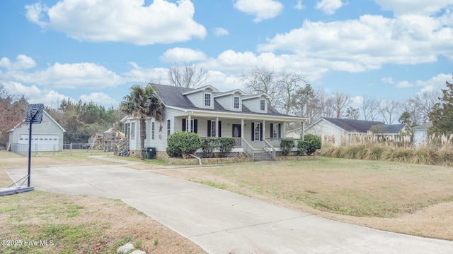 view of front facade featuring covered porch, a detached garage, and a front lawn