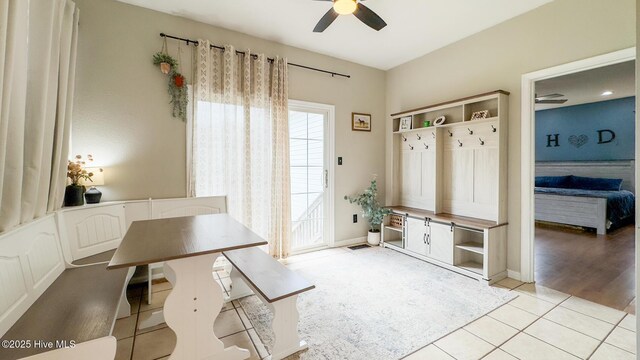 bedroom featuring light wood finished floors, ceiling fan, a barn door, and baseboards