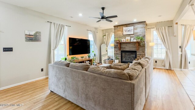 sitting room featuring a large fireplace, wooden walls, baseboards, and wood finished floors