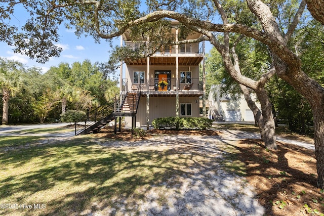 view of front facade featuring a balcony, stairway, and a front yard