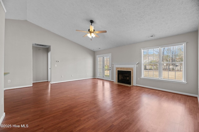 unfurnished living room featuring vaulted ceiling, a textured ceiling, ceiling fan, dark wood-type flooring, and a fireplace