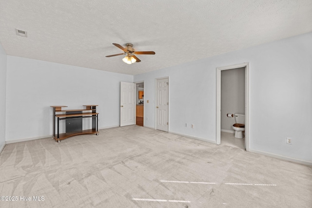 carpeted bedroom featuring ceiling fan, ensuite bath, and a textured ceiling