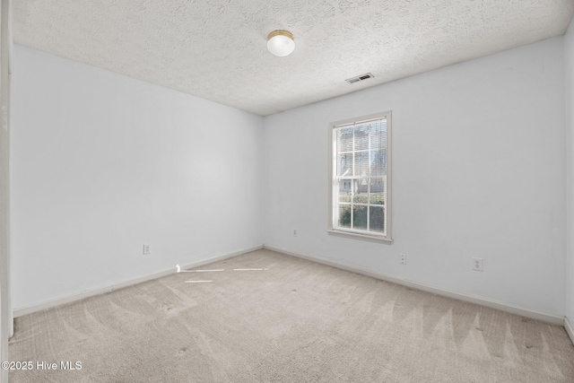 spare room featuring a textured ceiling and light colored carpet