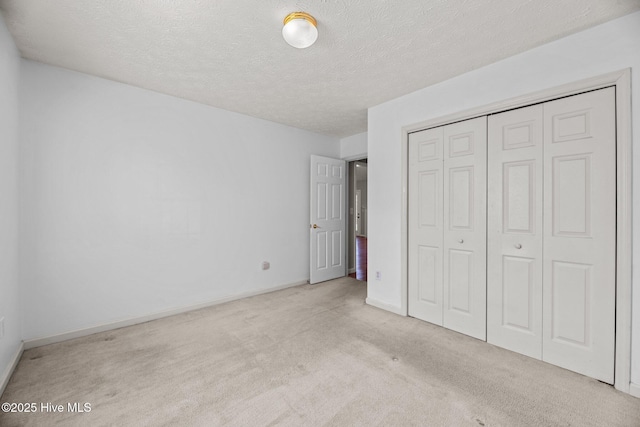 unfurnished bedroom with a closet, a textured ceiling, and light colored carpet