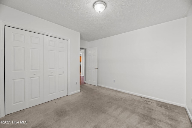 unfurnished bedroom with a textured ceiling, light carpet, and a closet