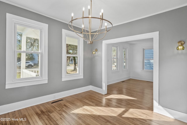 unfurnished dining area featuring ornamental molding, light wood-type flooring, a chandelier, and visible vents
